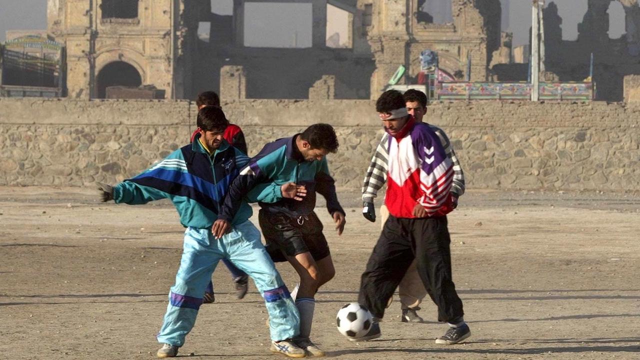 Männer spielen im Januar 2002 in dem zerstörten Stadion von Kabul Fußball.
