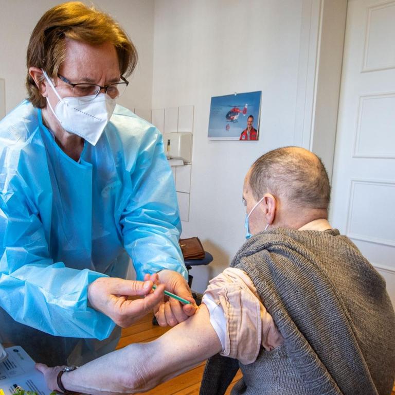 Eine Mitarbeiterin eines mobilen Impfteam spritzt einem Senioren in der Hausarztpraxis den Corona-Impfstoff von Biontech/Pfizer.