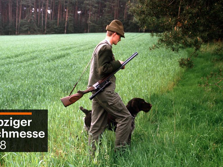 Ein Jäger geht mit geschulterter Flinte und seinem Jagdhund "bei Fuß" an einem Feld am Waldrand entlang. (undatierte Aufnahme)