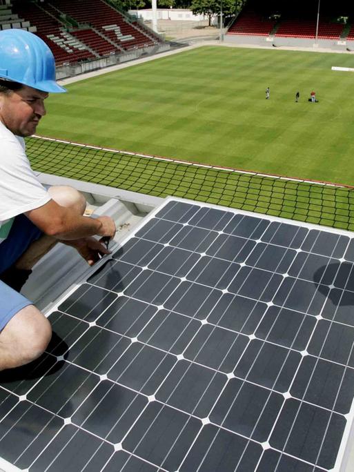 Alternative Energie auch in der Bundesliga: Auf dem Dach des Mainzer Bruchwegstadions befestigen zwei Bauarbeiter ein Modul einer Solaranlage.