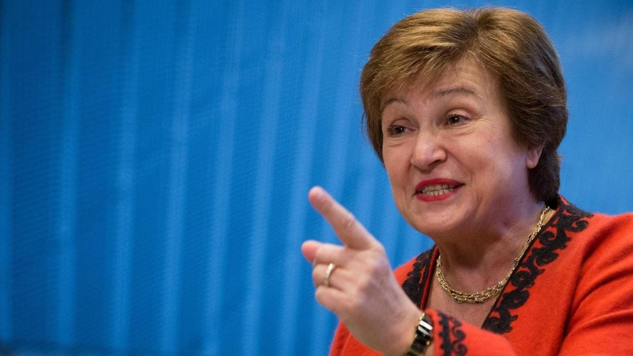 Kristalina Georgiewa, IWF-Chefin, vor einer blauen Wand; sie trägt einen roten Blazer und zeigt mit dem Zeigefinger der linken Hand in die Luft.