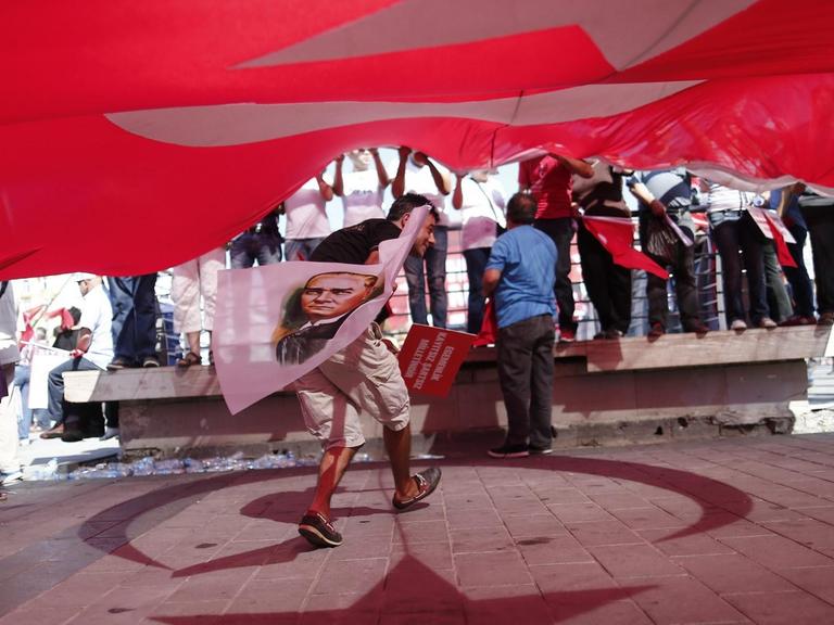 Ein Demonstrant steht unter einer türkischen Flagge und hält eine Fahne mit dem Konterfei von Staatsgründer Atatürk in der Hand.