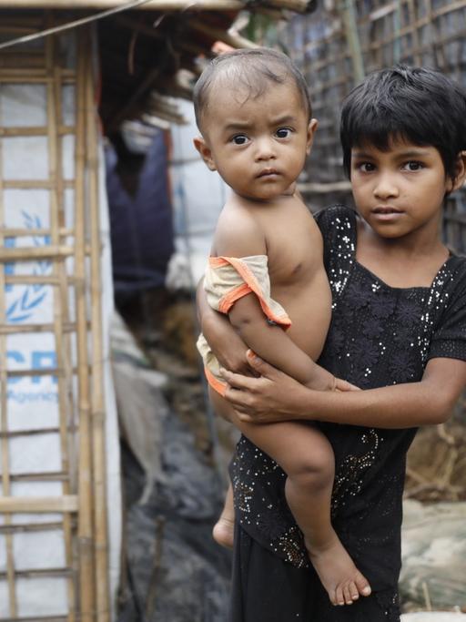 Ein Flüchtlingsmädchen der Rohingya hält ein Kleinkind auf dem Arm. Das Bild stammt aus dem Kutupalong-Flüchtlingslager im Bezirk Cox's Basar in Bangladesch im Juni 2018.