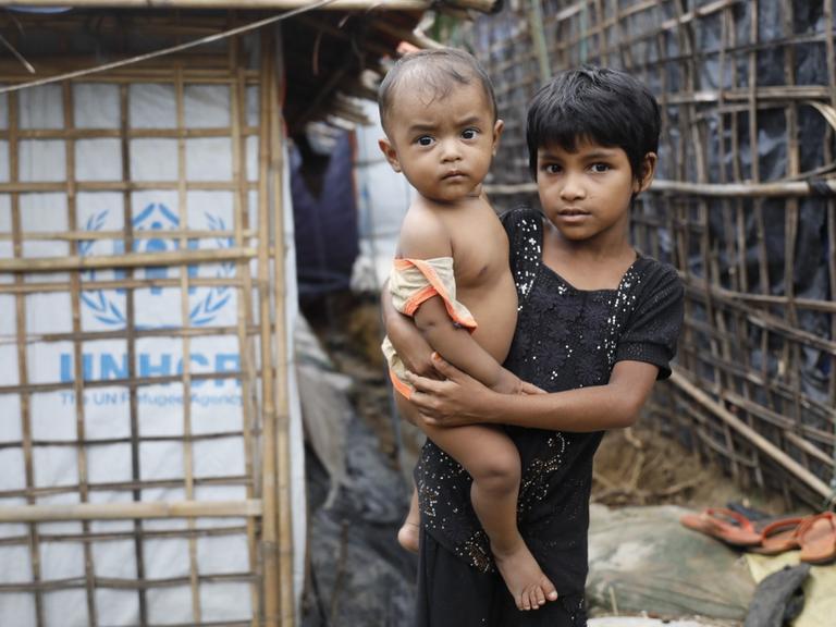 Ein Flüchtlingsmädchen der Rohingya hält ein Kleinkind auf dem Arm. Das Bild stammt aus dem Kutupalong-Flüchtlingslager im Bezirk Cox's Basar in Bangladesch im Juni 2018.