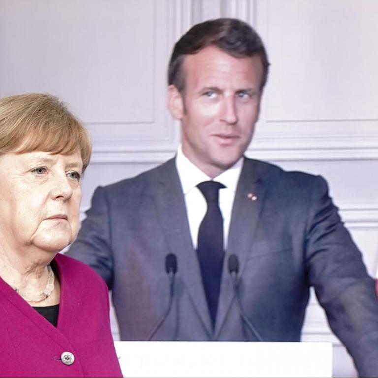 Bundeskanzlerin Angela Merkel (CDU), vor einem Bildschirm, auf dem Frankreichs Präsident Emmanuel Macron per Video zu einer Pressekonferenz zugeschaltet ist. 