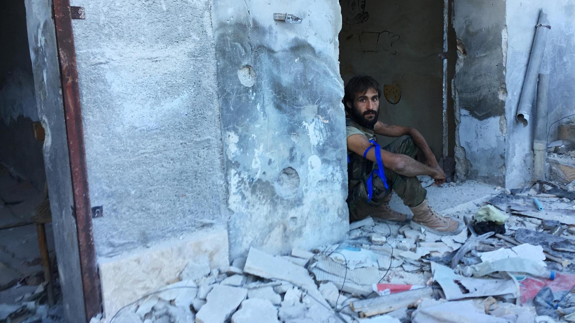 Ein Kämpfer sitzt im Eingang eines zerstörten Hauses im palästinensischen Flüchtlingslager Handarat im Südosten von Aleppo.