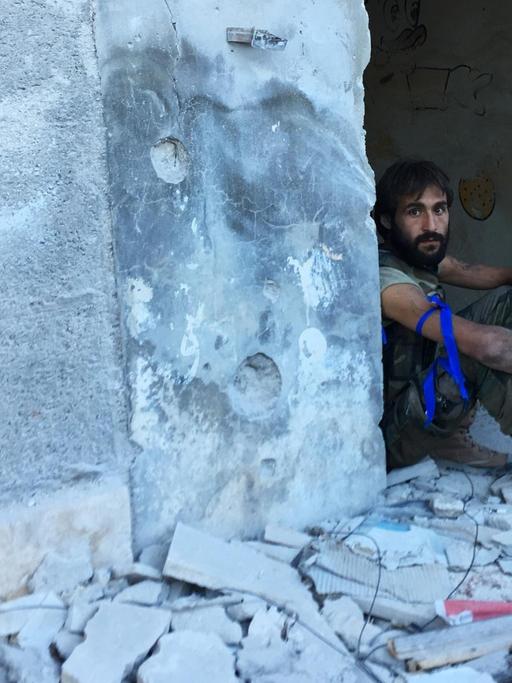 Ein Kämpfer sitzt im Eingang eines zerstörten Hauses im palästinensischen Flüchtlingslager Handarat im Südosten von Aleppo.