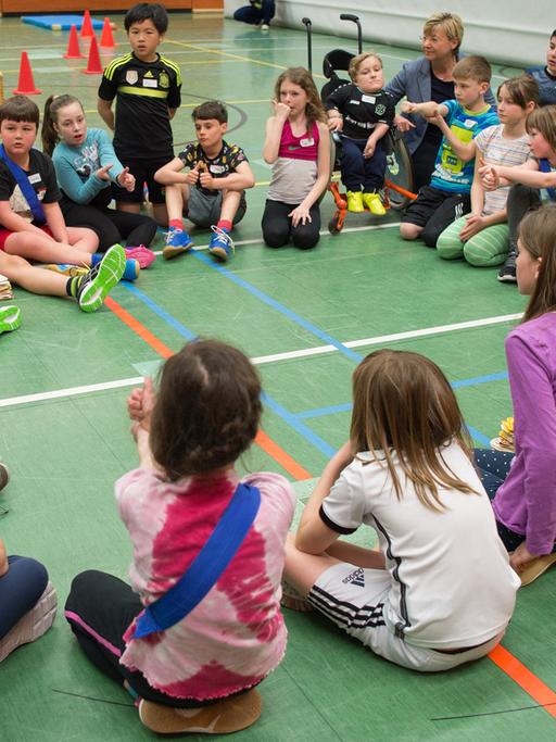 Die niedersächsische Kultusministerin Frauke Heiligenstadt (SPD, Hintergrund Mitte) sitzt am 27.04.2016 in der Sporthalle der Schule IGS Roderbruch in Hannover (Niedersachsen) während einer inklusiven Sportstunde mit Schülern in einem Kreis.