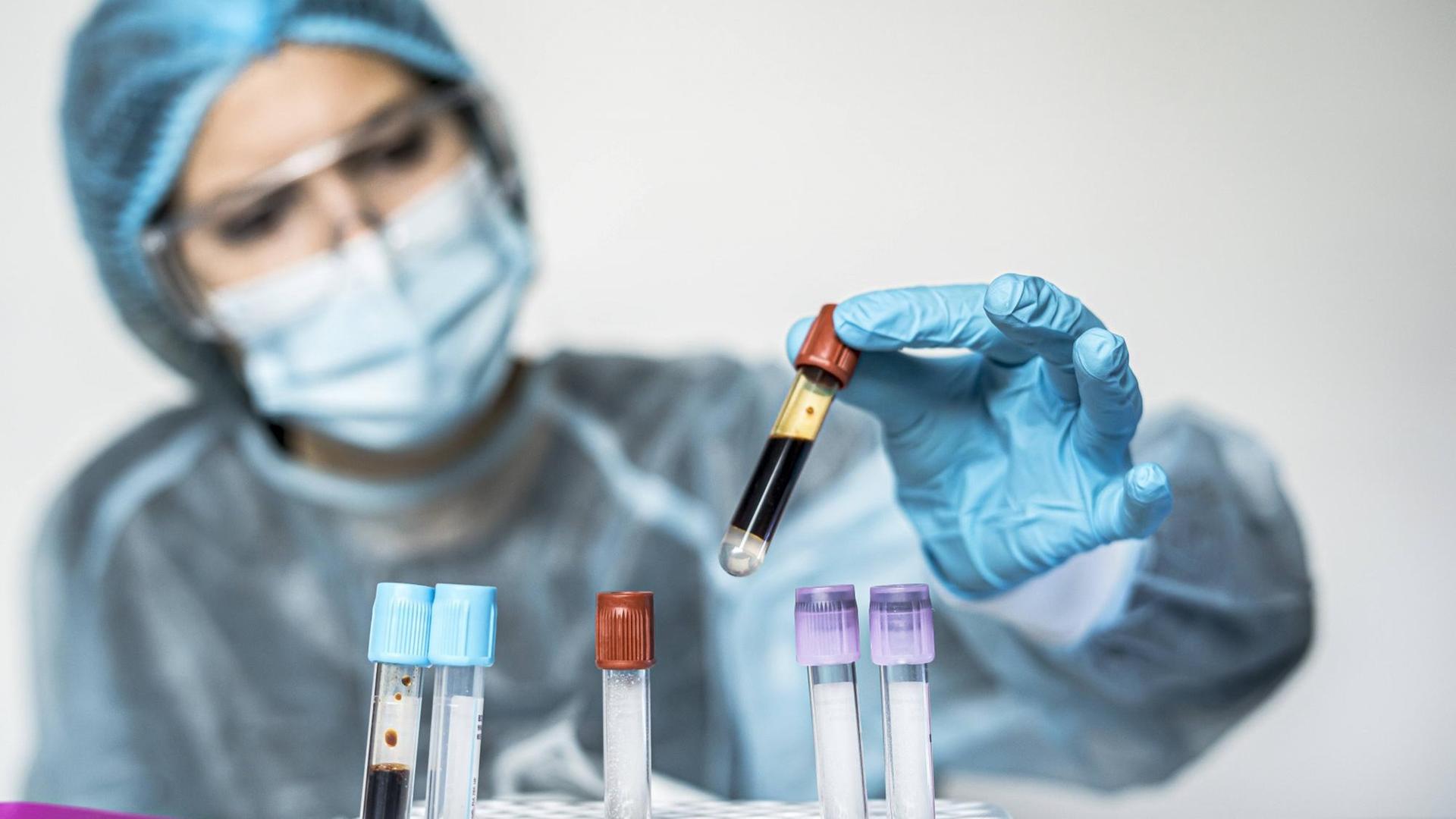 Blood test tube with label of Covid-19 also known as coronavirus or novel corona in scientist hand in laboratory. Female scientist is wearing highly protective suit, gloves, mask and glasses. Madrid, Community of Madrid, Spain PUBLICATIONxINxGERxSUIxAUTxONLY CR_JFOMNK210106B-595792-01 ,model released, Symbolfoto