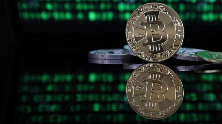Ein Bitcoin vor einem Monitor.
