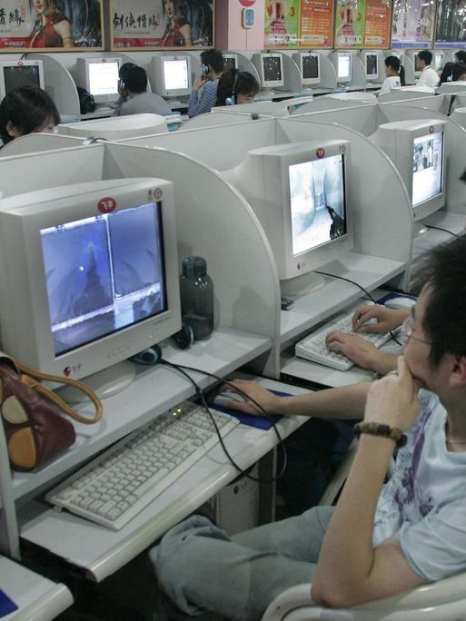 Blick in ein chinesisches Internetcafé: In einer Halle sind in langen Reihen Plätze mit Computern aufgebaut. Junge Menschen sitzen an den Rechnern.