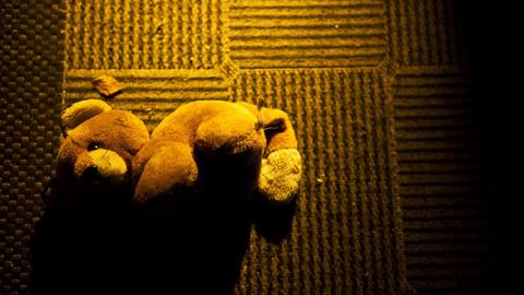 Ein Teddy am Boden im warmen Licht der Morgensonne, welches durch die Haustür aus Glas auf den Flur fällt.