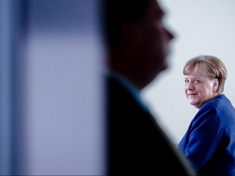 Bundeskanzlerin Angela Merkel geht grinsend um eine Ecke.