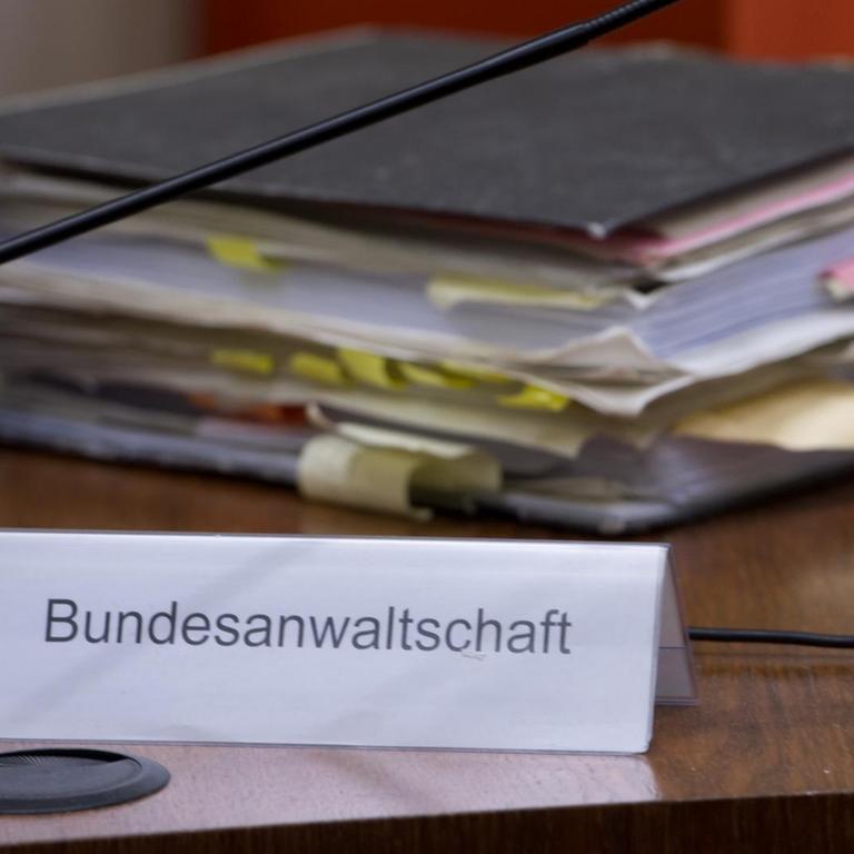 Ein voller Aktenordner liegt im Gerichtssaal im Oberlandesgericht in München auf dem Platz der Bundesanwaltschaft.