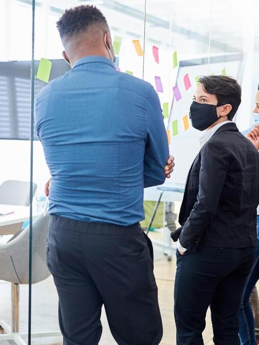 Kreativteam im Büro an einer Glaswand mit Zetteln