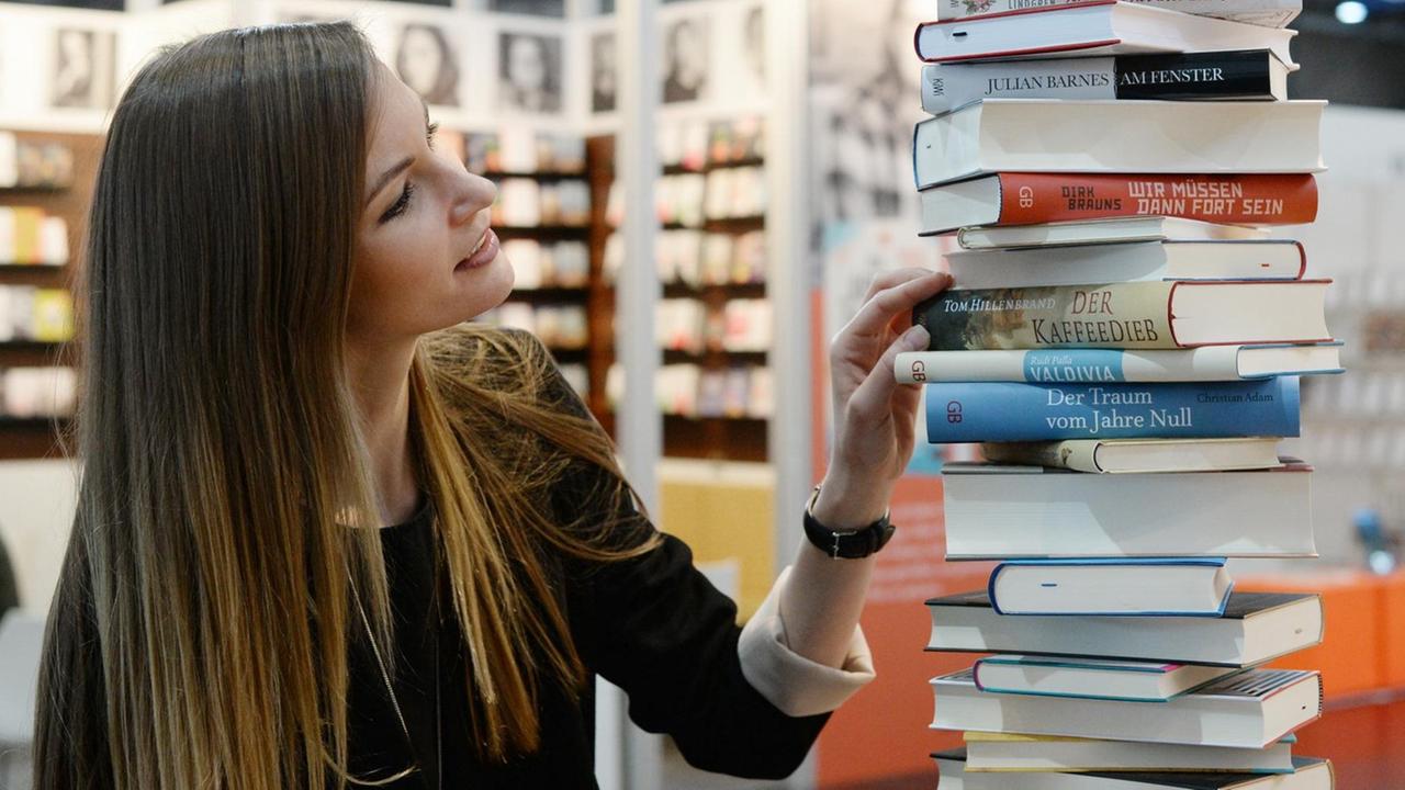 Ein Frau schaut sich auf der Leipziger Buchmesse (2016) Literatur an.
