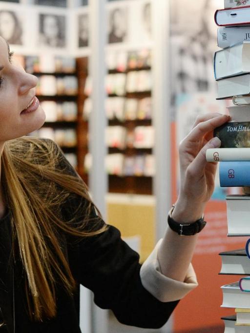 Ein Frau schaut sich auf der Leipziger Buchmesse (2016) Literatur an.