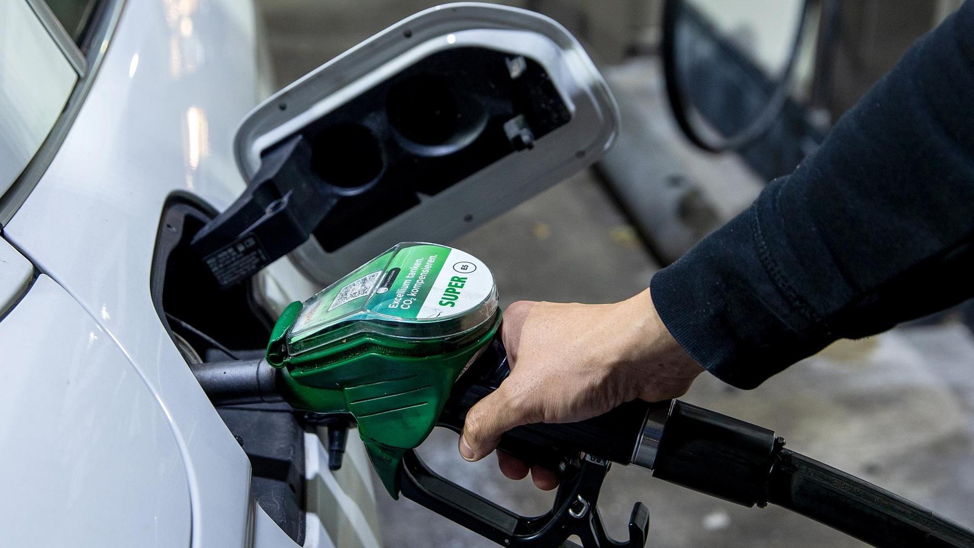 Ein Autofahrer tankt ein Auto mit Benzin Super E5 an einer Tankstelle.