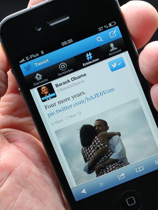 Smartphone auf dessen Display die Twitter-Nachricht "Four more years" von Barack Obama angezeigt wird.