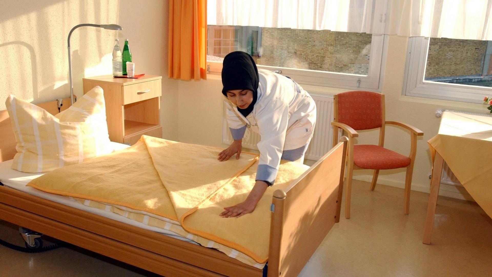 Muslimische Altenpflegerin richtet ein Bett im einem türkischen Altenpflegeheim in Berlin.