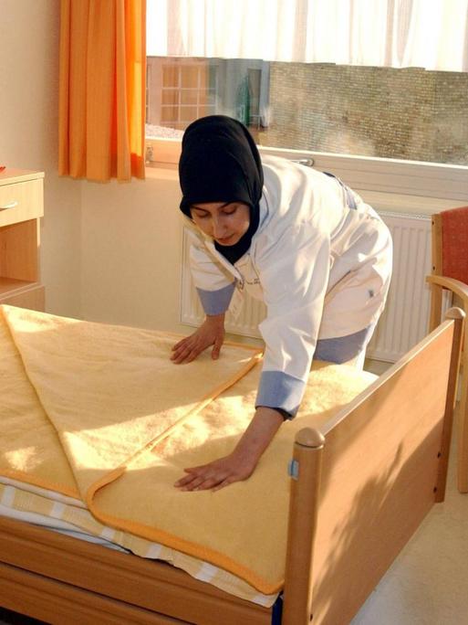 Muslimische Altenpflegerin richtet ein Bett im einem türkischen Altenpflegeheim in Berlin.