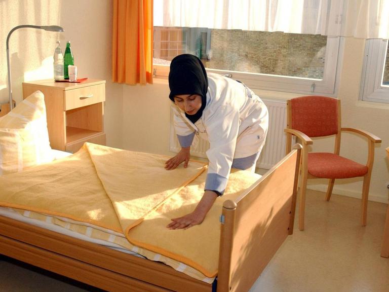 Muslimische Altenpflegerin richtet ein Bett im einem türkischen Altenpflegeheim in Berlin.