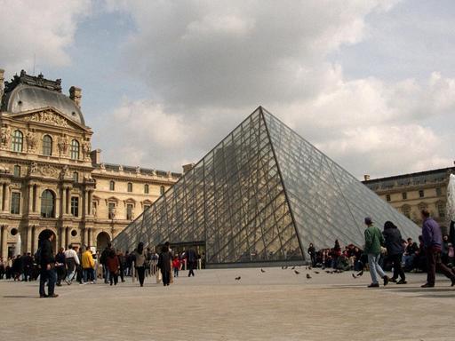 Touristen warten vor der gläsernen Pyramide im Hof des Louvres