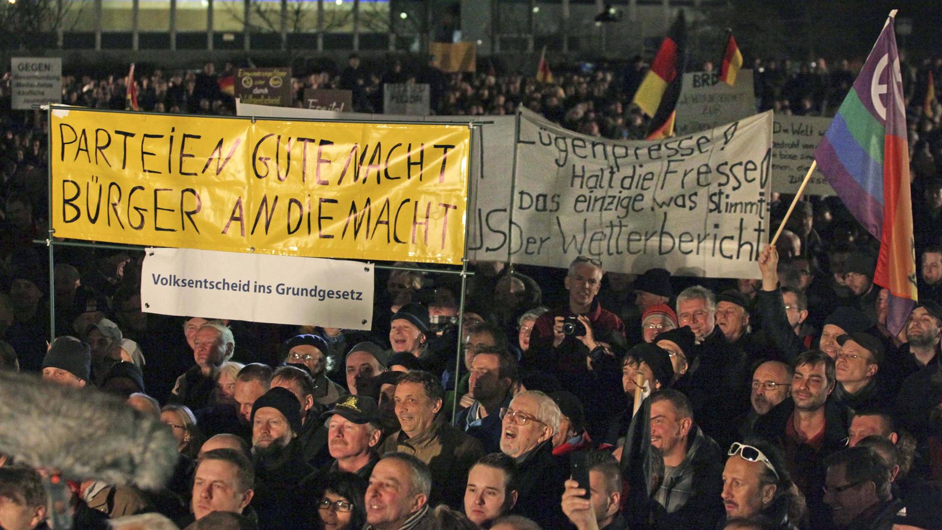 Pegida-Demonstranten in Dresden halten am 15. Dezember 2014 Banner hoch.