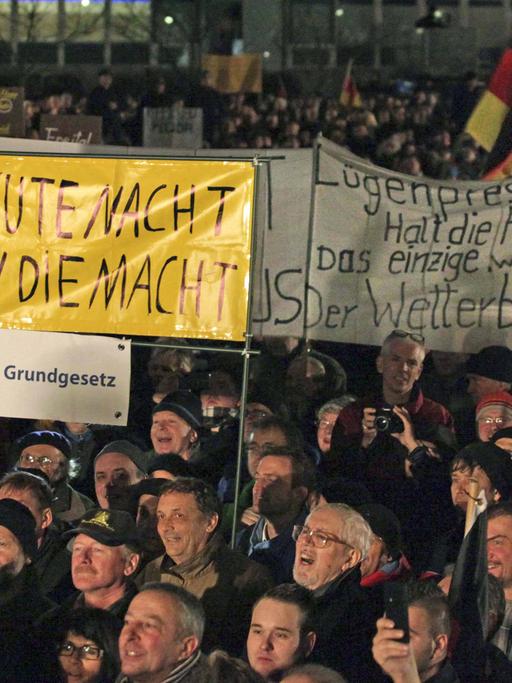 Pegida-Demonstranten in Dresden halten am 15. Dezember 2014 Banner hoch.