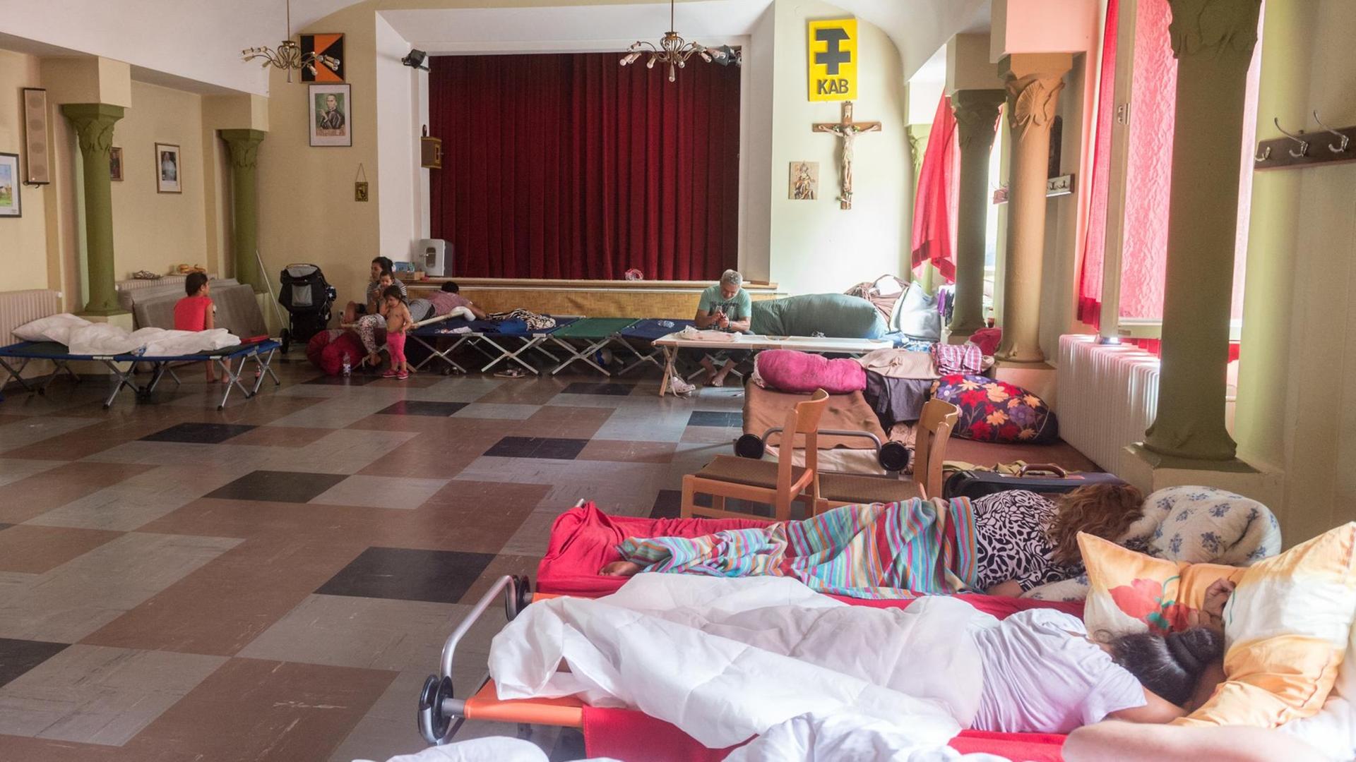 Betten stehen in einem großen Raum eines Pfarrheims in Regensburg.