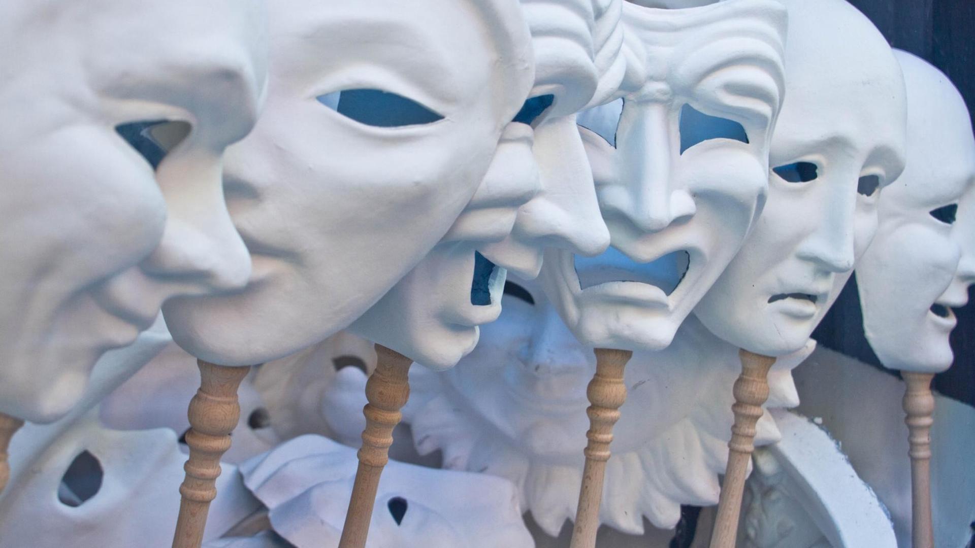 Weiße Karnevalsmasken drücken verschiedene Emotionen aus.