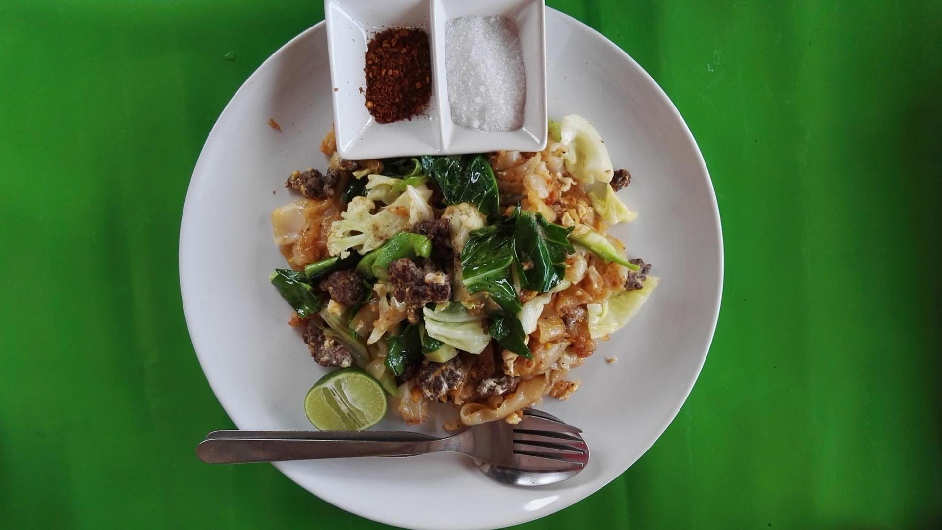 Thailändisches Essen auf einem weißen Teller.