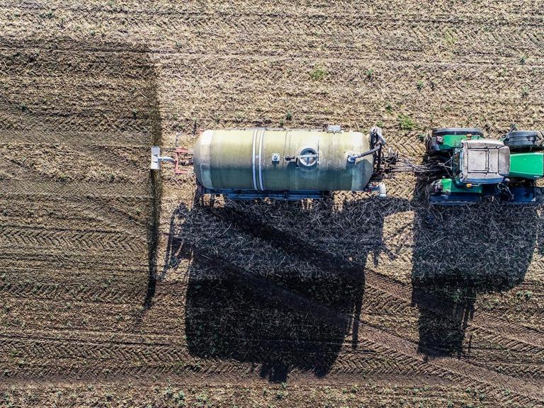 Ein Trecker düngt ein Feld mit Gärresten aus einer Biogasanlage