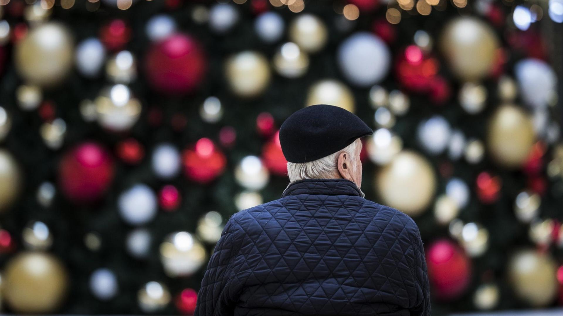 Ein Mann sitzt allein auf einer Bank vor einem geschmückten Weihnachtsbaum, aufgenommen am 17. Dezember 2019 in Berlin.