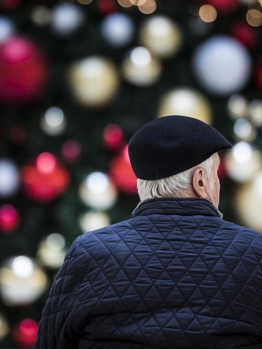Ein Mann sitzt allein auf einer Bank vor einem geschmückten Weihnachtsbaum, aufgenommen am 17. Dezember 2019 in Berlin.