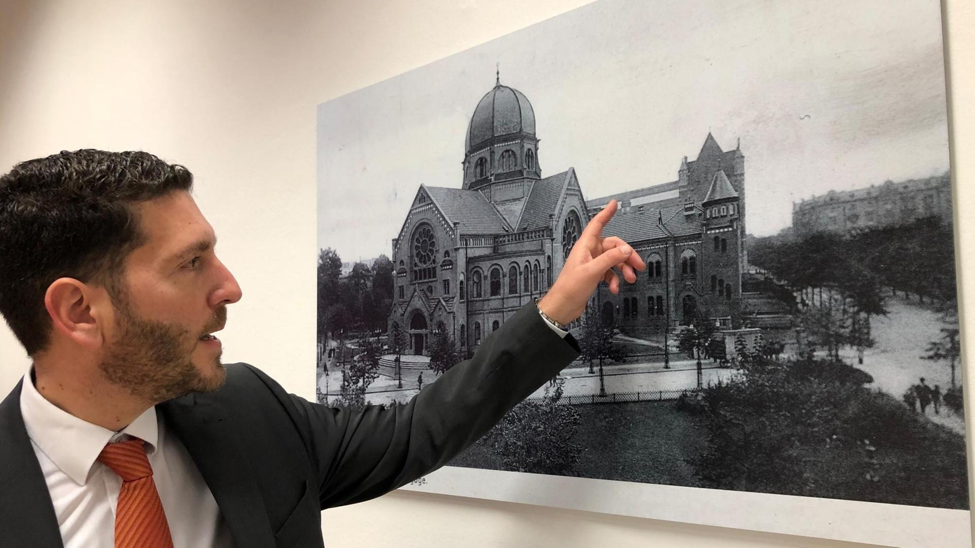 Philipp Stricharz, 1. Vorsitzender der Jüdischen Gemeinde Hamburg, zeigt auf ein historisches Foto der Bornplatzsynagoge.