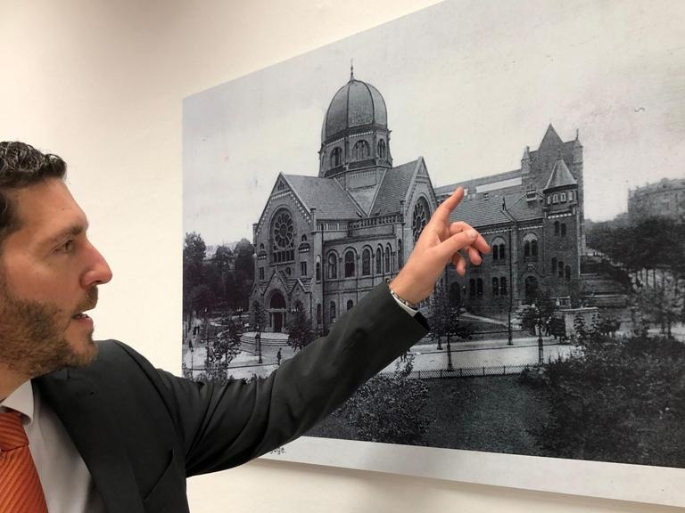 Philipp Stricharz, 1. Vorsitzender der Jüdischen Gemeinde Hamburg, zeigt auf ein historisches Foto der Bornplatzsynagoge.