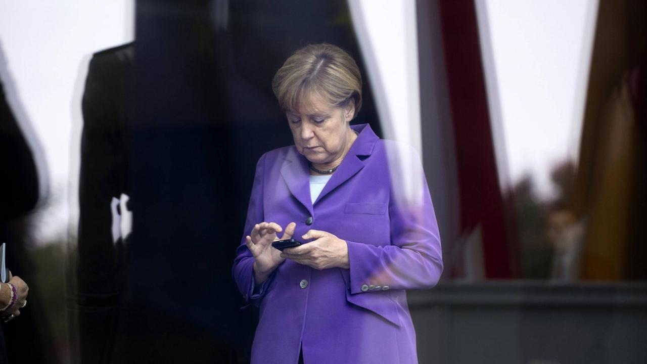 Angela Merkel schaut auf ihr Handy.