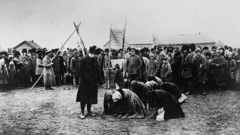 Mutmaßlich hungernde russische Frauen knien vor einem Mann, vermutlich Offizier der Hilfsorganisation American Relief Administration