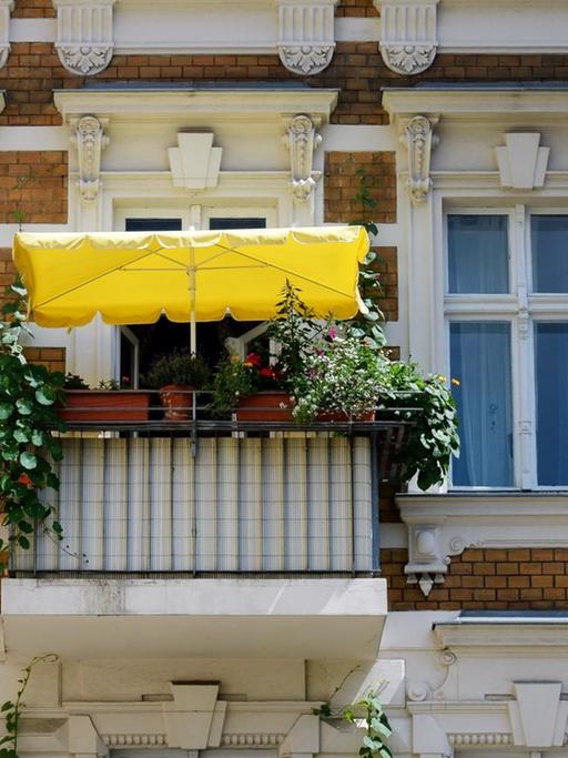 Ein bepflanzter Balkon mit einem gelben Sonnenschirm, fotografiert am 06.07.2017 in Berlin Mitte.