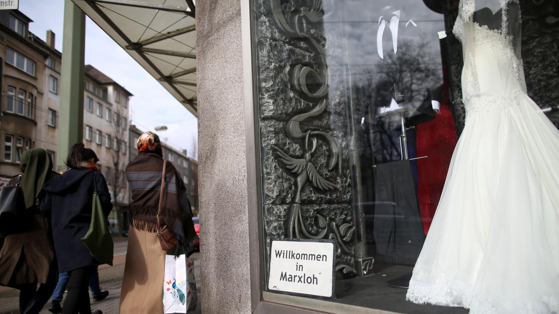 Passanten gehen über die Weseler Straße im Duisburger Stadtteil Marxloh an einem Geschäft für Brautmoden vorbei.