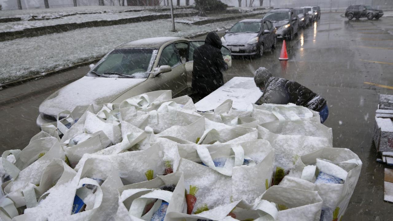 Mitarbeiter der "Food Bank of Lincoln" verteilen während eines Schneesturms Lebensmittel an Personen, die in Autos vorfahren.