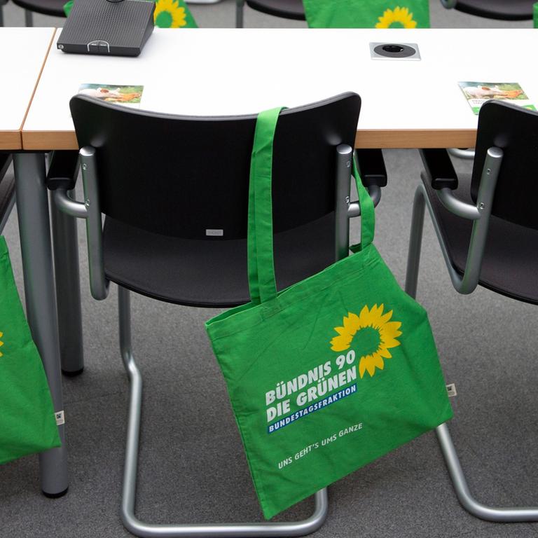 Stoffbeutel mit dem Grünen-Logo hängen im vor Beginn einer  Fraktionssitzung 2012 im Bundestag über den Stuhllehnen.