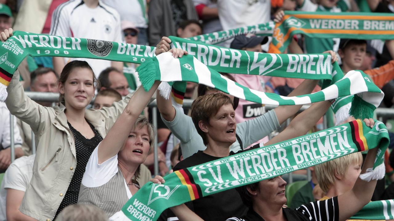 Weibliche Fans von Werder Bremen halten ihre Fanschals in die Höhe.