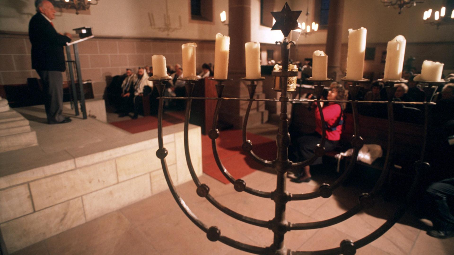 Ein jüdischer Gottesdienst in der Synagoge in Worms mit einem neunarmigen Leuchter im Vordergrund.