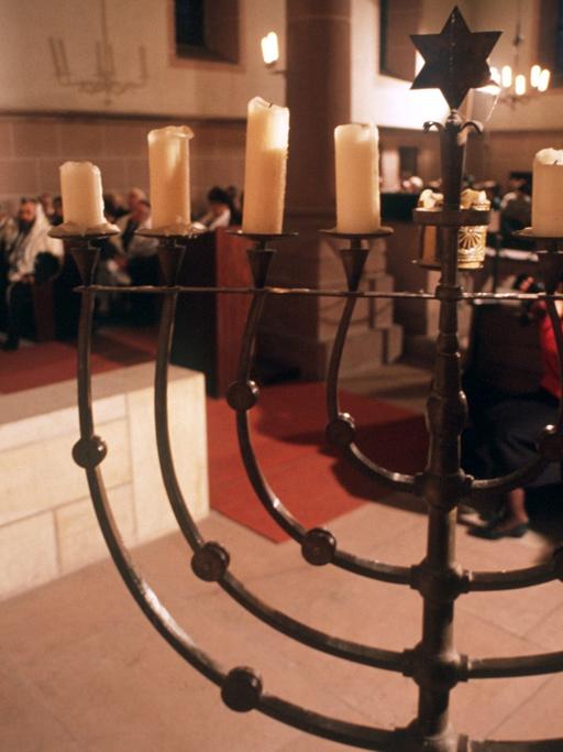 Ein jüdischer Gottesdienst in der Synagoge in Worms mit einem neunarmigen Leuchter im Vordergrund.