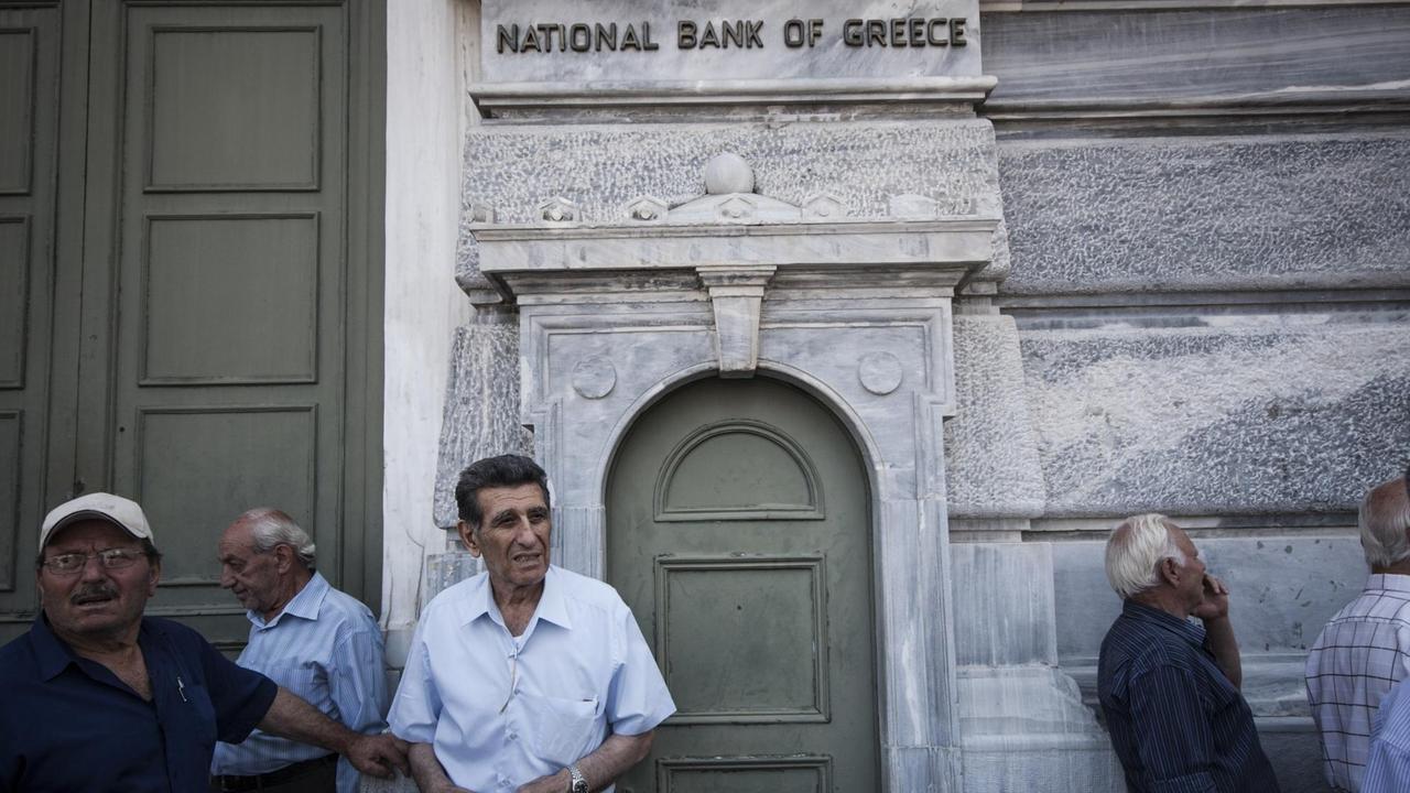 Ältere Männer warten vor einer Filiale der Griechischen Nationalbank, um ihre Pensionen abzuholen.