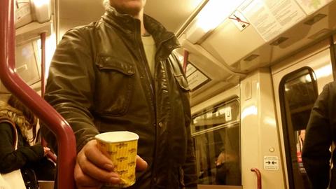 Ein Bettler bittet in der U-Bahn Fahrgäste eine Spende in seinen Becher zu werfen.