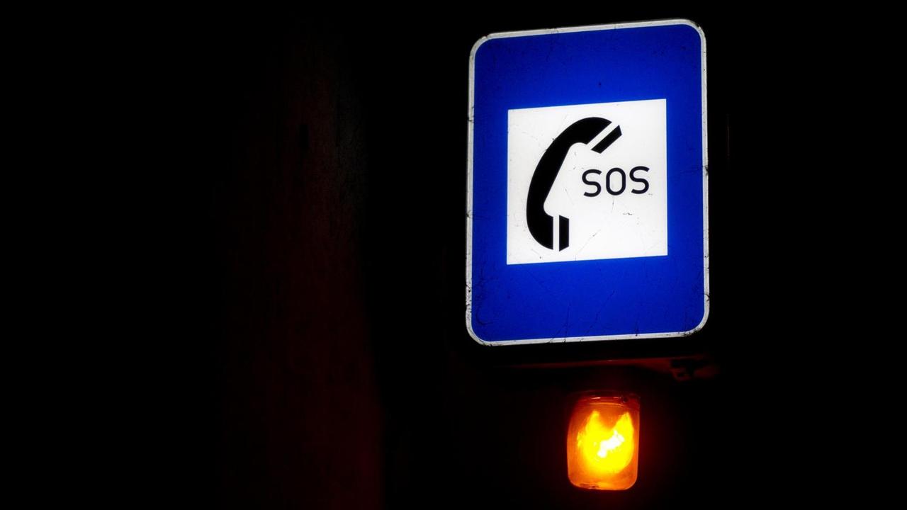 Ein leuchtendes "SOS"-Schild vor schwarzem Hintergrund.