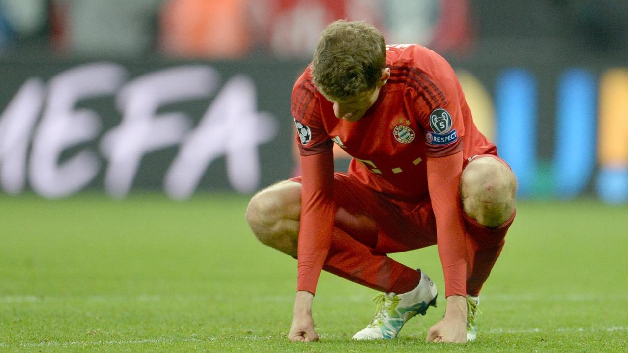 Müller hockt enttäuscht auf dem Rasen und lässt den Kopf hängen.